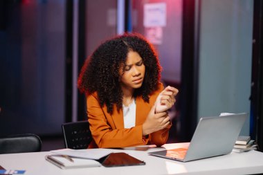 İş kadını fazla mesai yapıyor, masa başında bilgisayar kullanıyor ve lamba ışığında fazla mesai yapıyor.