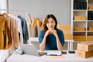 Başlangıçta küçük işletme KOBİ 'si, dizüstü bilgisayar kullanan girişimci kadın paket ürün kutusu hazırlamak için çevrimiçi alışveriş siparişini alır ve kontrol eder.