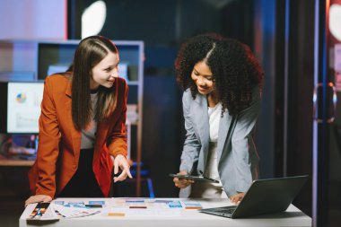 İş kadınları modern ofiste bilgisayarlı bir proje üzerinde birlikte çalışıyorlar.
