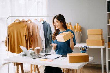 Başlangıçta küçük işletme KOBİ 'si, dizüstü bilgisayar kullanan girişimci kadın paket ürün kutusu hazırlamak için çevrimiçi alışveriş siparişini alır ve kontrol eder.