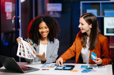  UX geliştiricisi ve ui tasarımcısı modern ofiste müşteri özeti ve renk kodu ile mobil uygulama arayüzü kablo tasarımı hakkında beyin fırtınası yapıyorlar