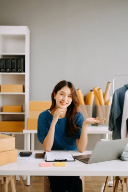 Başlangıçta küçük işletme KOBİ 'si, dizüstü bilgisayar kullanan girişimci kadın paket ürün kutusu hazırlamak için çevrimiçi alışveriş siparişini alır ve kontrol eder.