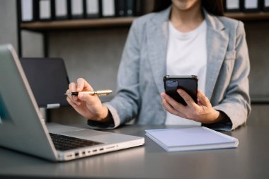 Ofiste çalışan iş kadınları, ofiste akıllı telefon ve dizüstü bilgisayar kullanıyorlar.
