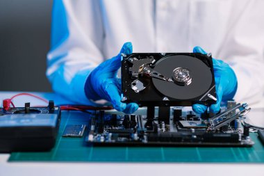 Teknisyenin masasında sabit disk ve bir bilgisayar ana kartı var. Veri, donanım ve bilgi teknolojisi kavramı
