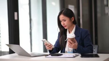 Ofiste bilgisayar ve akıllı telefon kullanan Asyalı mutlu bir iş kadını. 