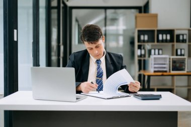 Modern ofiste çalışan olgun bir iş adamı. Masasında dizüstü bilgisayar var.