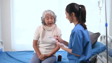 Asyalı doktor hastanedeki Asyalı yaşlı kadını muayene ederken not alıyor.