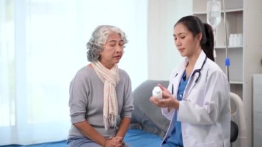 Asyalı doktor hastanedeki yaşlı bir Asyalı kadına ilaç veriyor.