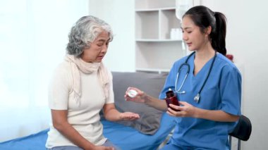 Asyalı doktor hastanedeki yaşlı bir Asyalı kadına ilaç veriyor.