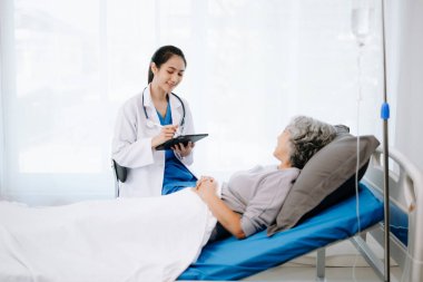 Doktor ve Asyalı yaşlı kadın hasta ve doktor hastane koğuşlarında danışmanlık yapıyor..