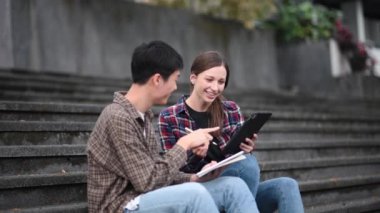 Kampüs parkındaki aletleri kullanarak birlikte okuyan genç üniversite öğrencileri.