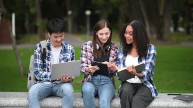 Kampüs parkında birlikte okuyan genç üniversite öğrencileri.