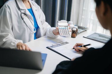 Sağlık giderleri ve ücret kavramları. Akıllı bir doktorun eli, sabahları hastane masrafları için hesap makinesi, akıllı telefon ve tablet kullandı.