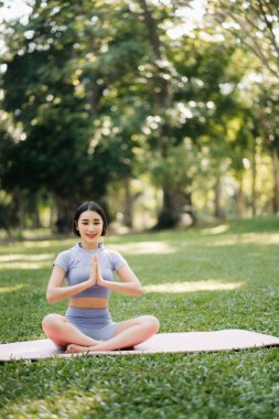 Asyalı genç bir kadın yaz bahçesinde lotus poz verirken meditasyon yapıyor. İç huzur ve farkındalık kavramı