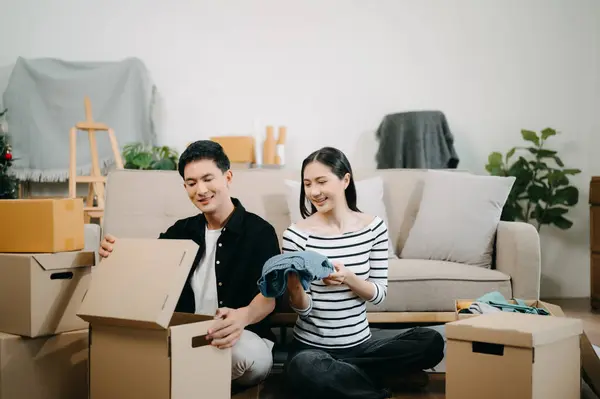 Young couple with big boxes moving into a new house. Happy asian man and woman in home Interior