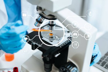 Modern laboratuvarda mikroskopla çalışan bir doktor. Sanal ekranda sağlık teknolojisi, dijital simgeler 