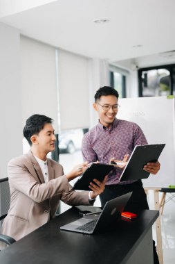 Nazik yönetici yönetici, Asyalı erkek pazarlama yöneticisiyle birlikte modern ofiste iş çözümlerini paylaşır ve tartışır.