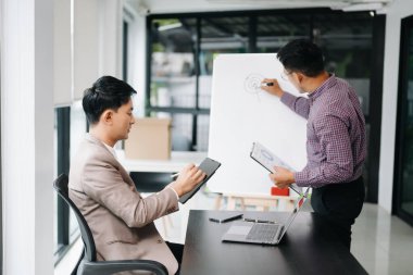 Nazik yönetici yönetici, Asyalı erkek pazarlama yöneticisiyle birlikte modern ofiste iş çözümlerini paylaşır ve tartışır.