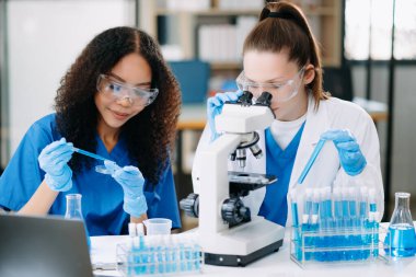 Laboratuvarda mikroskop ve test örnekleriyle çalışan iki bilim adamı veya tıbbi teknisyen..