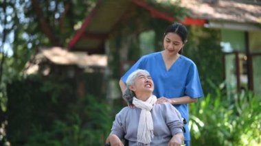 Genç Asyalı hemşire hastane parkında tekerlekli sandalyede yaşlı bir kadına masaj yapıyor. Kıdemli sağlık hizmeti kavramı