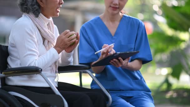 Asyalı Doktor Hastane Parkında Tekerlekli Sandalyedeki Yaşlı Bir Kadını Muayene — Stok video