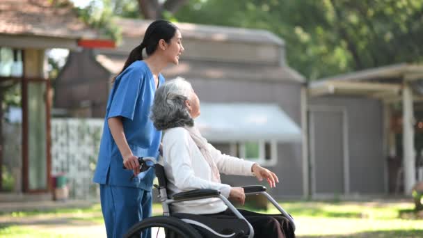 在医院公园照顾坐轮椅的老年妇女的年轻亚洲护士 高级保健概念 — 图库视频影像