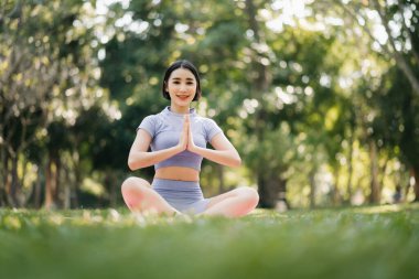 Bahçede yoga yapan genç bir kadının portresi. Kadın mutluluğu. Parkta arka plan bulanıklaştı. Sağlıklı yaşam tarzı ve rahatlama kavramı