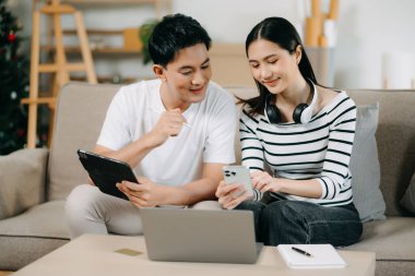 Asyalı Kadın, erkek meslektaşımla yeni projeyi tartışıyor. Genç bir kadın, ofisteki kanepede finanslı genç Asyalı bir adamla konuşuyor.