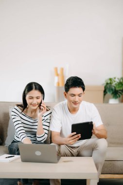 Asyalı Kadın, erkek meslektaşımla yeni projeyi tartışıyor. Genç bir kadın, ofisteki kanepede finanslı genç Asyalı bir adamla konuşuyor.