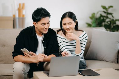 Asyalı Kadın, erkek meslektaşımla yeni projeyi tartışıyor. Genç bir kadın, ofisteki kanepede finanslı genç Asyalı bir adamla konuşuyor.