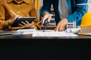 Ofiste mimari tartışan ve dijital tablet kullanan meslektaşlar