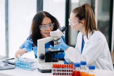 Laboratuvarda mikroskop ve test örnekleriyle çalışan iki bilim adamı veya tıbbi teknisyen..