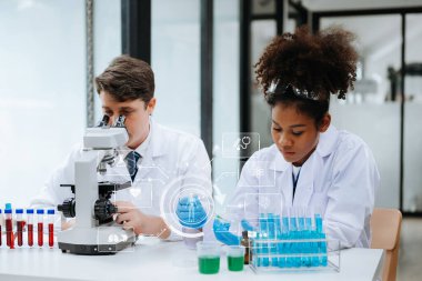 Yetişkin erkek doktor ve Afrikalı kadın hemşire mikroskop kullanarak birlikte araştırma yapıyorlar. Hastanedeki çeşitli tıp uzmanlarına yoğunlaşmışlar. Tıbbi simgeleri olan sanal ekran