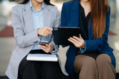 Şehirde dijital tablet ve akıllı telefon kullanarak konuşan iki başarılı iş kadını 