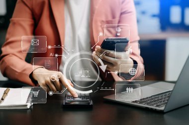 Ofiste çalışan iş kadınları, ofiste akıllı telefon ve dizüstü bilgisayar kullanıyorlar.