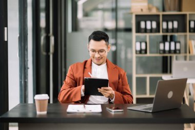 Genç çekici bir adam iş yerinde dijital tablet kullanıyor. Ofisteki işine odaklan.