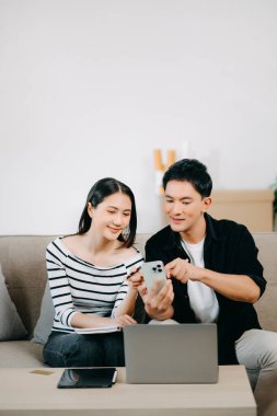 Asyalı Kadın, erkek meslektaşımla yeni projeyi tartışıyor. Genç bir kadın yurt merkezindeki kanepede Asyalı genç bir adamla konuşuyor.