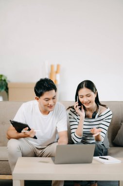 Asyalı Kadın, erkek meslektaşımla yeni projeyi tartışıyor. Genç bir kadın yurt merkezindeki kanepede Asyalı genç bir adamla konuşuyor.