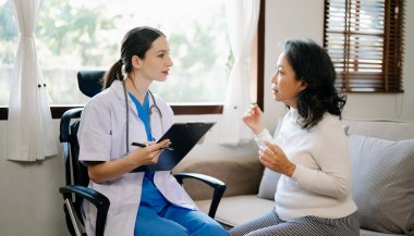 Kıdemli kadın oturma odasında bir doktor tarafından muayene ediliyor.