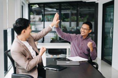 İş adamları konferans odasında yeni bir başlangıç projesi üzerinde çalışıyor ve beşlik çakıyor.
