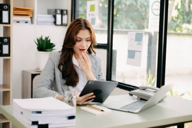 Asyalı iş kadını ofisteki dijital tablet dizüstü bilgisayarın çalışmasından memnun ve memnun.
