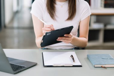 Modern ofiste işyerinde tablet üzerinde çalışan kendine güvenen bir iş kadını.