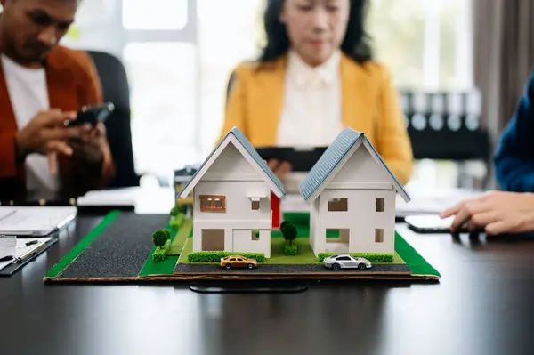 stock image Real estate broker agent presenting house model to customer and making sign insurance form agreement in office