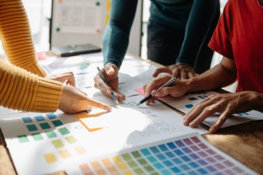  UX geliştiricileri ve ui tasarımcıları modern ofiste müşteri özeti ve renk kodu ile mobil uygulama arayüzü kablo tasarımı hakkında beyin fırtınası yapıyorlar.