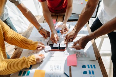  UX geliştiricileri ve ui tasarımcıları modern ofiste müşteri özeti ve renk kodu ile mobil uygulama arayüzü kablo tasarımı hakkında beyin fırtınası yapıyorlar.