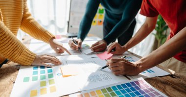  UX geliştiricileri ve ui tasarımcıları modern ofiste müşteri özeti ve renk kodu ile mobil uygulama arayüzü kablo tasarımı hakkında beyin fırtınası yapıyorlar.