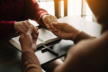 Kadın eli ve haçlı adam. Umut, inanç, Hıristiyanlık, din, kilise kavramı ve Tanrı 'ya dua. Tahta masada.