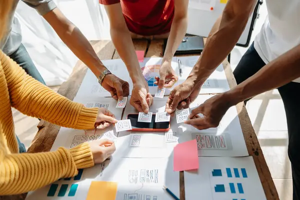  UX geliştiricileri ve ui tasarımcıları modern ofiste müşteri özeti ve renk kodu ile mobil uygulama arayüzü kablo tasarımı hakkında beyin fırtınası yapıyorlar.