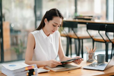 Ofiste çalışırken panoya bakan Asyalı kadın..