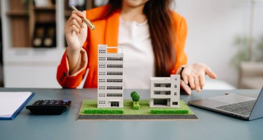 Emlak komisyoncusu, emlak kredisi teklifiyle ilgili sözleşme imzalama anlaşmasını, ev modelini sunar ve müşteriye danışmanlık yapar.